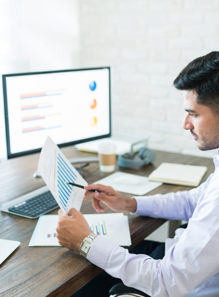 Handsome Latin businessman examining sales data while working at home